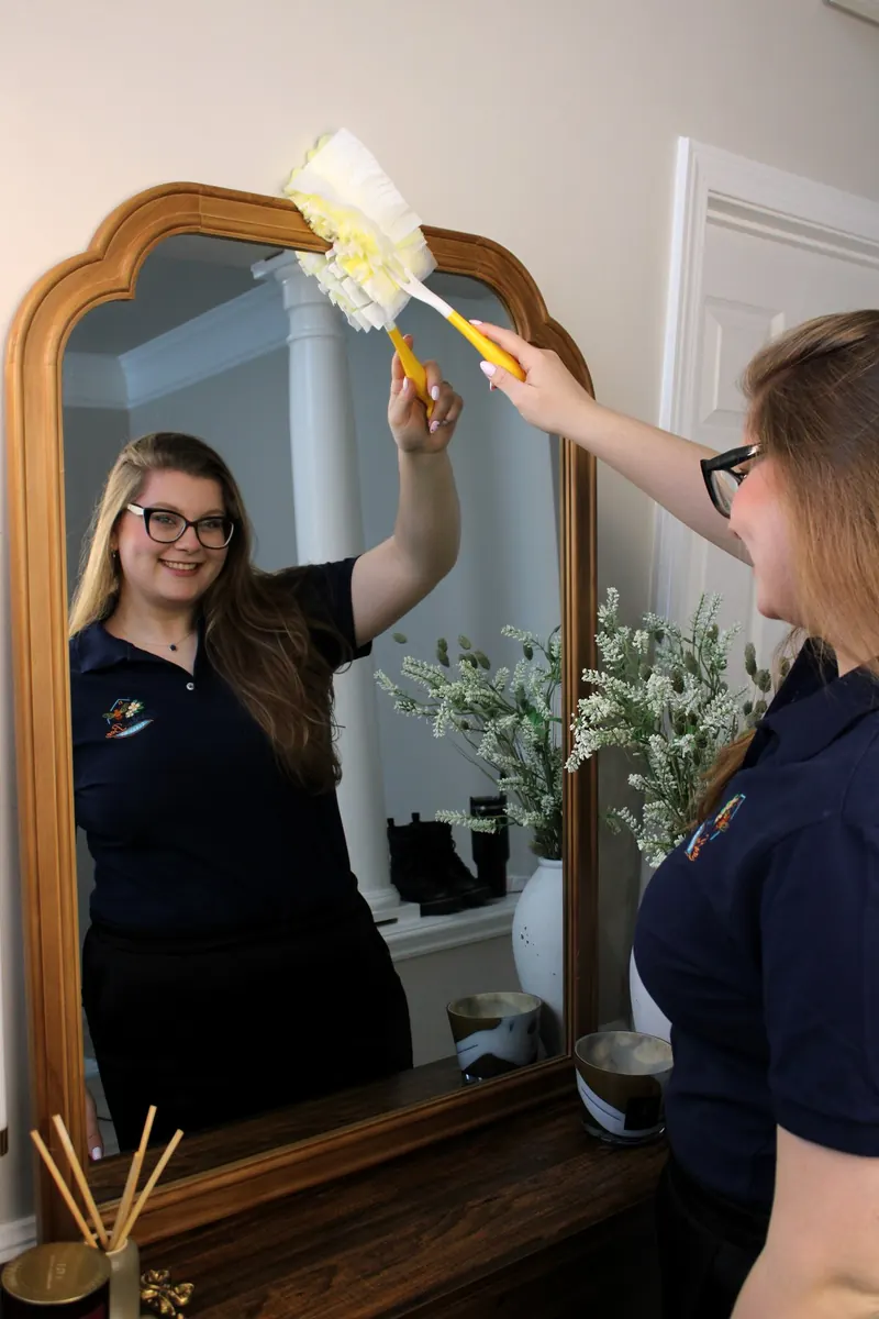 Ashley dusting a large mirror
